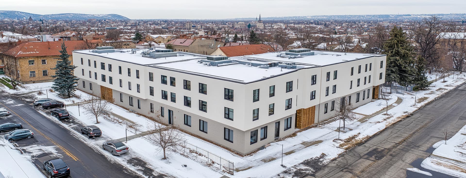 Snow-covered flat commercial roof on a Chicago-area building with rooftop drains and HVAC units — representing winter preparation for commercial roofs
